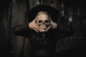 Hexe hält Totenschädel vor ihr Gesicht