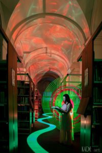 Lightpainting im Lesesaal der Universitätsbibliothek Leipzig. Model Mandy mit Buch in der Hand. Grün-rote Tube. Grüne Bodenspuren mit Malerrolle. Orannge/rote Decke