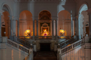 Lightpainting in der Bibliotheca Albertina zu sehen sind 3 florale Ornamente im Foyer der Bibliothek. Die Farben sind gelb mit roten und blauen Elementen. Das Bild ist sehr symmetrisch und klar